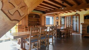 A dining area with wooden tables and chairs, a wooden ceiling with exposed beams, and a clock on the wall. - Holiday Home "Gîte du Tronquoy" with Private Terrace, Garden and Wi-Fi (Aix-en-Ergny)