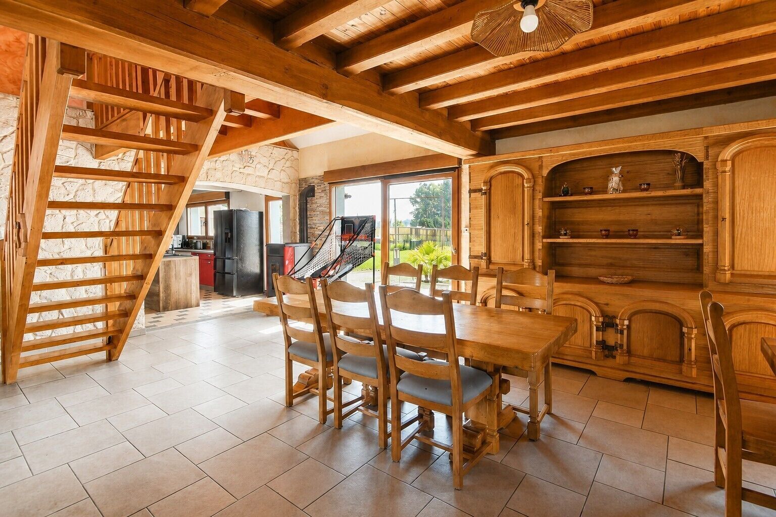 Een houten interieur met een eettafel en stoelen, een keukenhoek en een stenen muur.