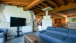 A living room with a stone wall, wooden ceiling beams, a television, a sofa, and a fireplace. - Holiday Home "Gîte du Tronquoy" with Private Terrace, Garden and Wi-Fi (Aix-en-Ergny)