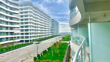 A modern multi-story hotel with a curved facade, a parking lot, and a green landscaped area.