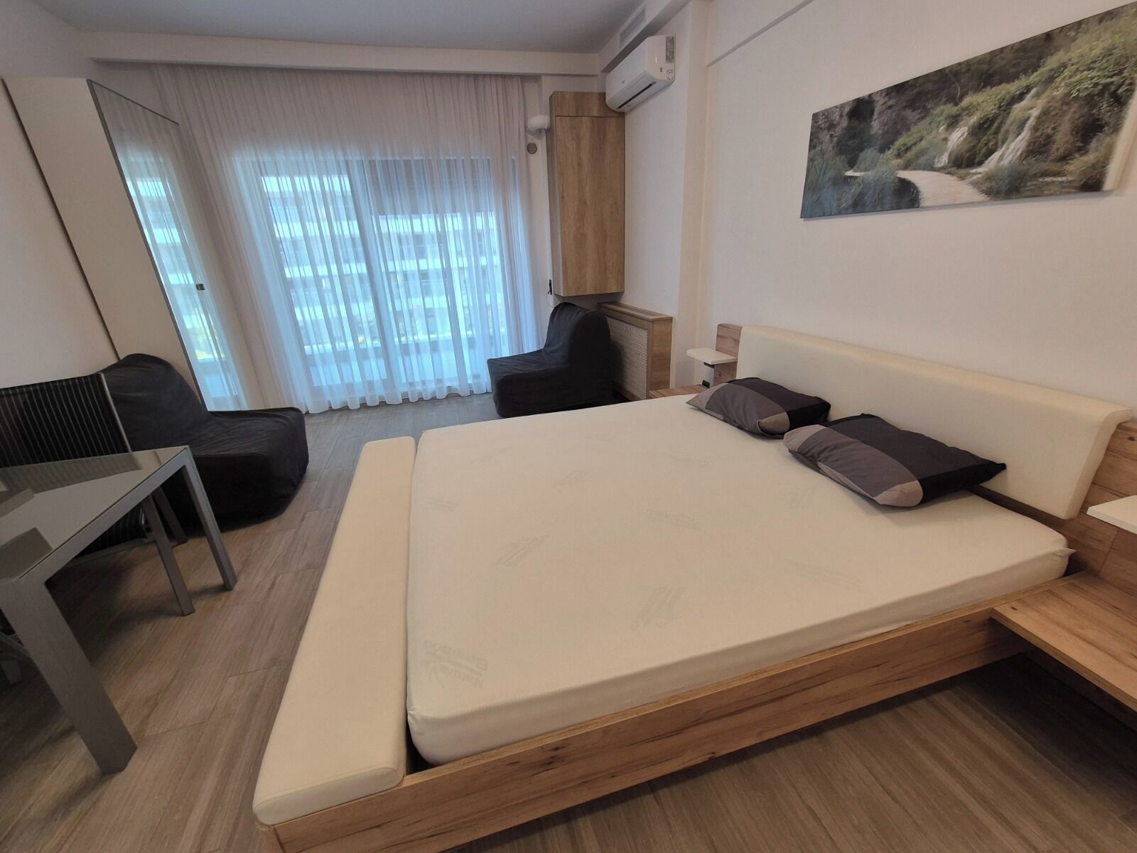 Una habitación de hotel moderna con una cama grande, un escritorio, una silla y un cuadro en la pared.
