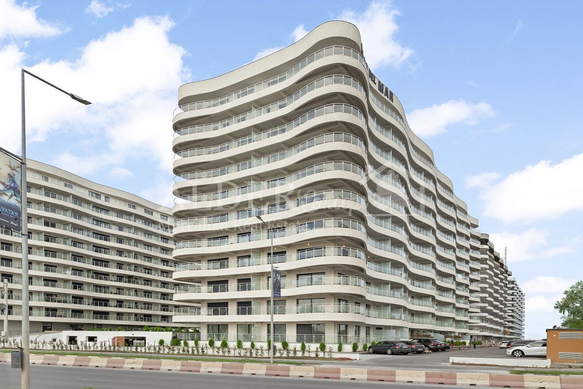 A modern multi-story hotel with a curved facade, numerous balconies, and a well-maintained exterior.