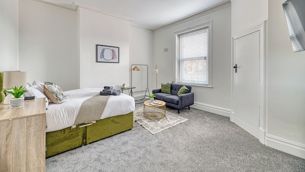 Une chambre à coucher avec un lit, un canapé, une petite table et une fenêtre.