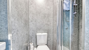 Une salle de bain moderne équipée de toilettes, d’une douche et d’un espace de douche clos par des parois de verre.