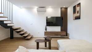 A modern living room with a staircase, a flat-screen TV, a wooden cabinet, and a sofa. - Villa Ruzarija with jacuzzi (Sukošan)