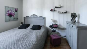 A bedroom with a bed, bedside table, lamp, and a dresser.