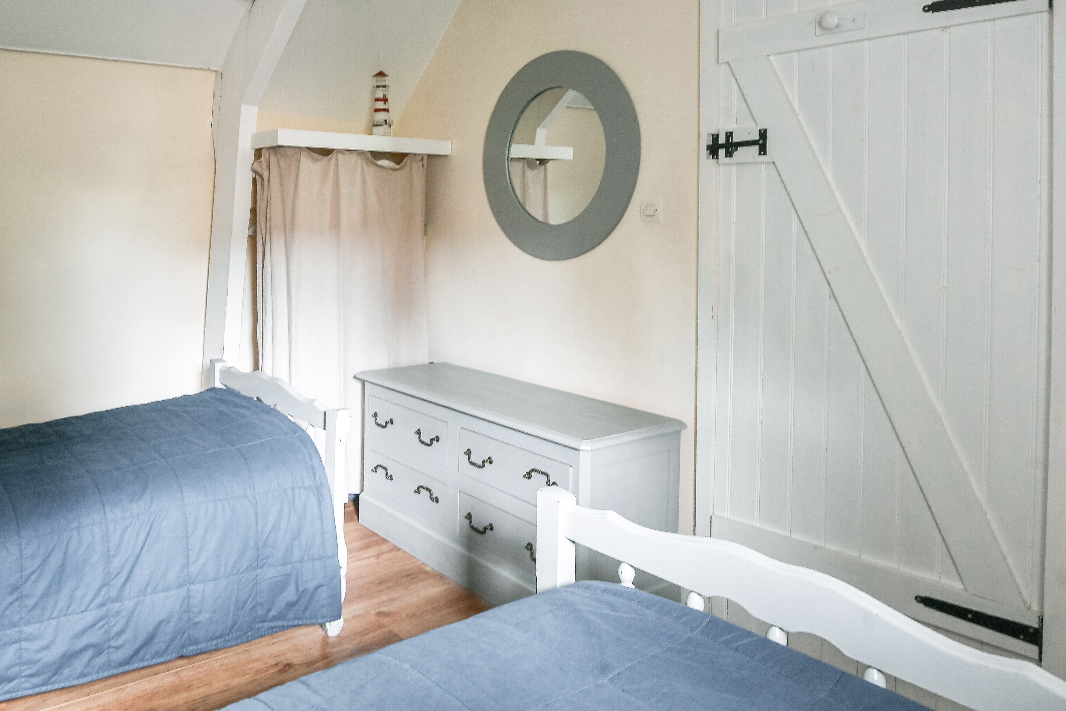 A bedroom with two beds, a dresser, a mirror, and a door.