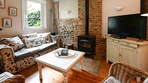 Un salon confortable avec un canapé, une table, un téléviseur, une cheminée et un mur en briques.