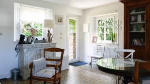 A kitchen with a coffee maker, a kettle, and a cabinet. There are two chairs and a table. - Cottages de la Croix l'Abbé, la Bergeronnette – Tranquil Duplex Retreat (Saint-Valery-sur-Somme)