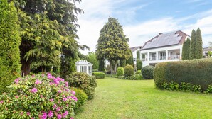 Ein gepflegter Garten mit verschiedenen Pflanzen und einem großen Baum in der Mitte.