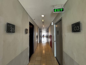 A hotel corridor with numbered doors, an exit sign, and a tiled floor. - Collection O Expressia Stay (South Tangerang)