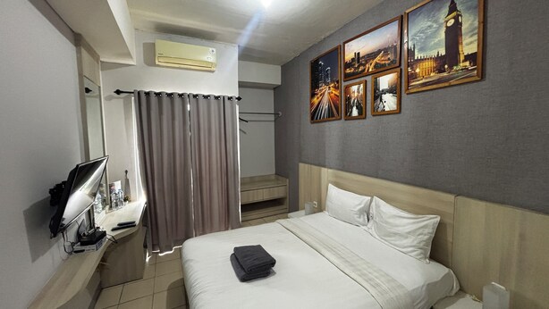 Habitación de hotel con cama, televisor, aire acondicionado, zona de ducha y una pared con imágenes.