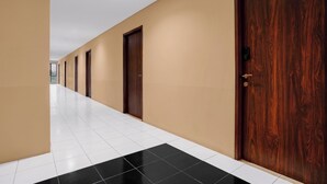 Un pasillo con puertas a un lado y piso de baldosas.