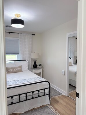 A bedroom with a bed, bedside table, lamp, and a ceiling light fixture. - Finely appointed 3-bedroom farmhouse with AC in charming Pleasant Hill (Sparta)