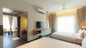 A hotel room with two beds, a TV, a ceiling fan, and a bathroom with a shower.