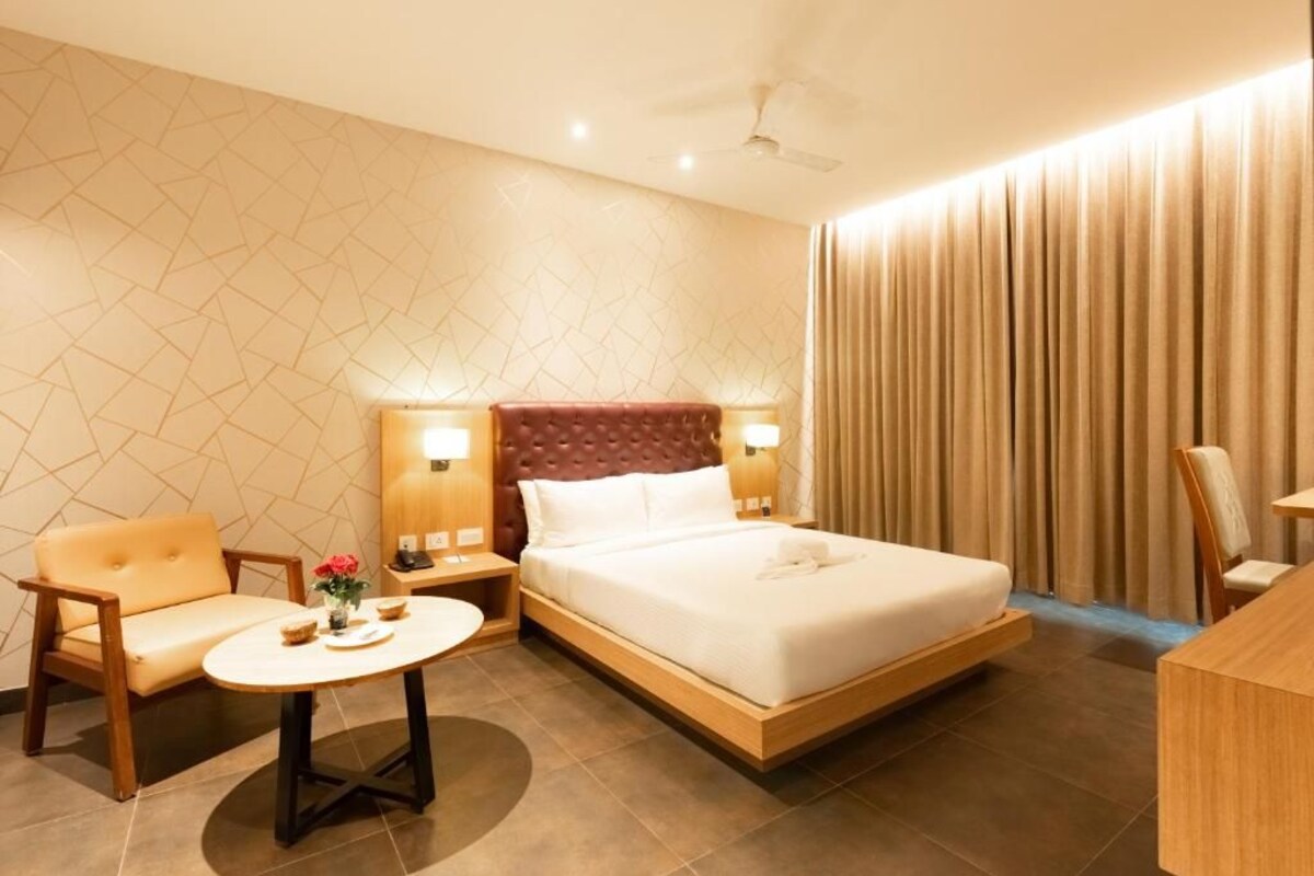 A hotel room with a bed, a sofa, a small table, and a chair.