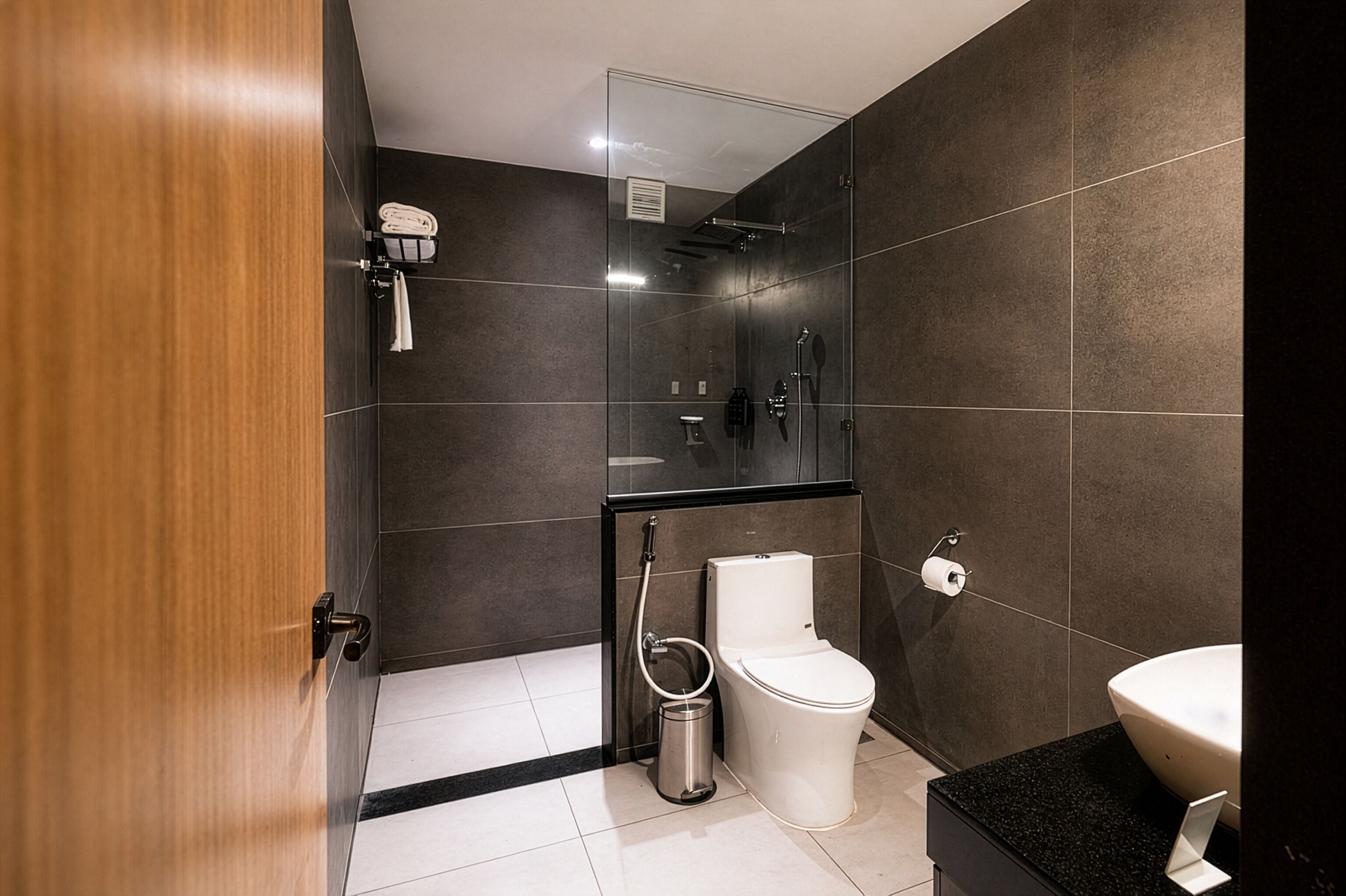 A modern bathroom with a glass shower enclosure, a toilet, a bidet, and a sink.