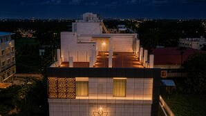 A multi-story hotel with a rooftop terrace, a visible entrance, and a sign indicating it is a hotel.
