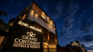 A hotel with a prominent sign reading 'Grand Continental Hotels & Resorts' and a logo with a leaf.