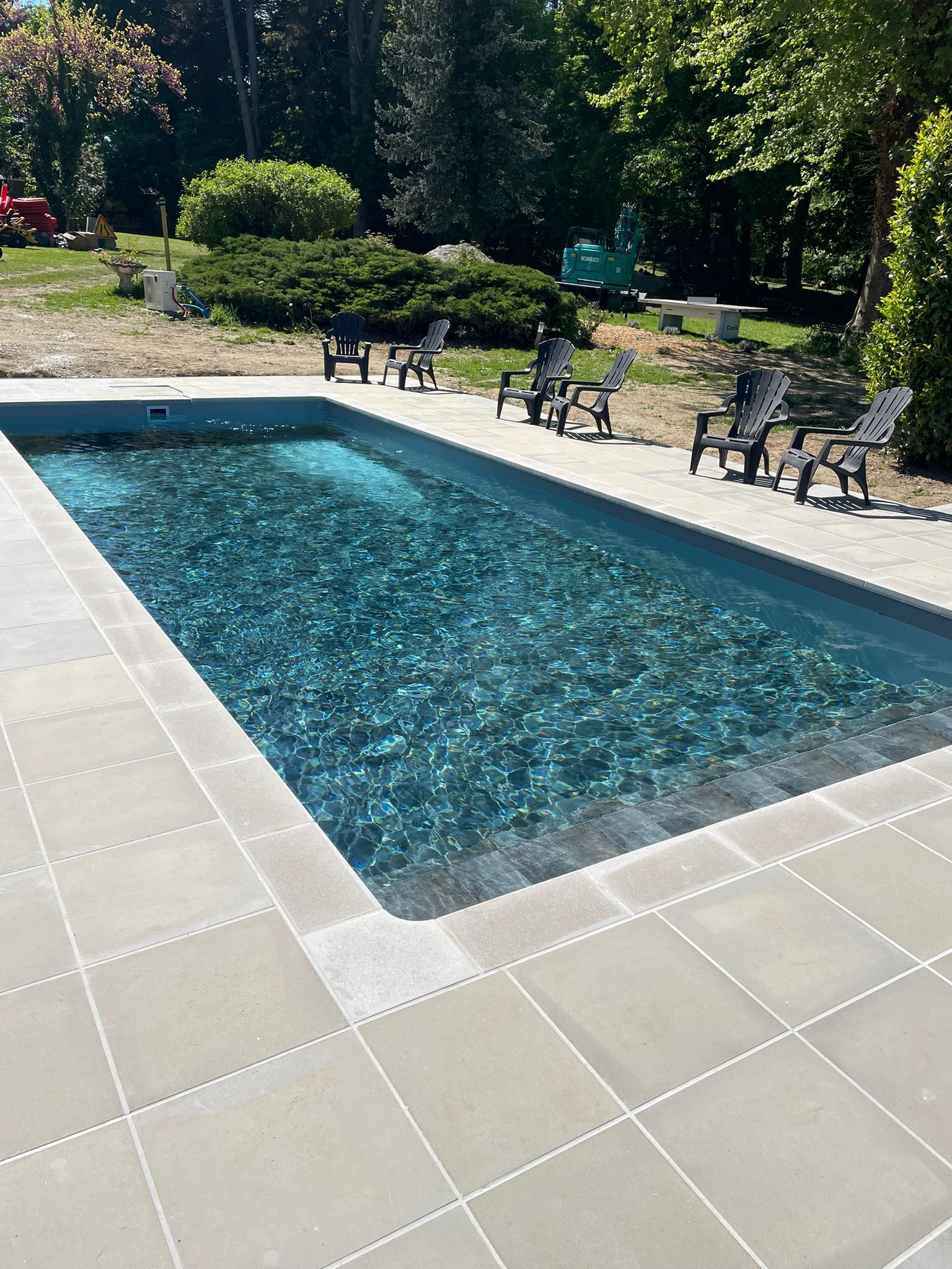 Una piscina rectangular con agua cristalina, rodeada por una solería de baldosas.