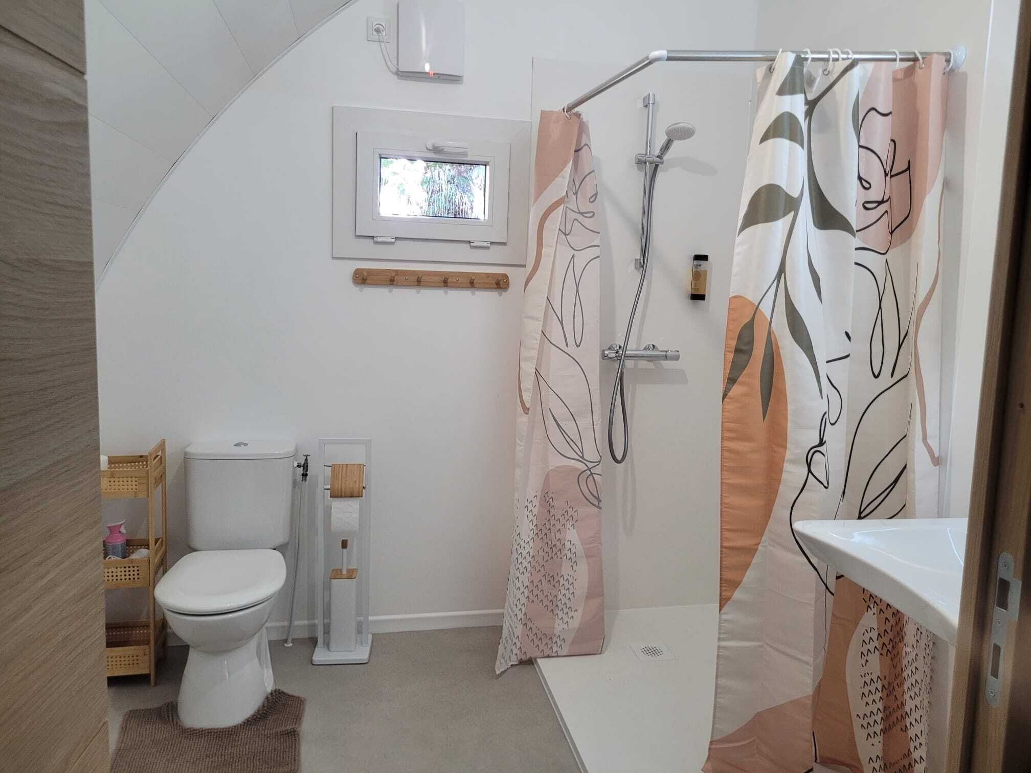 Un baño con inodoro, bidé, ducha y ventana.
