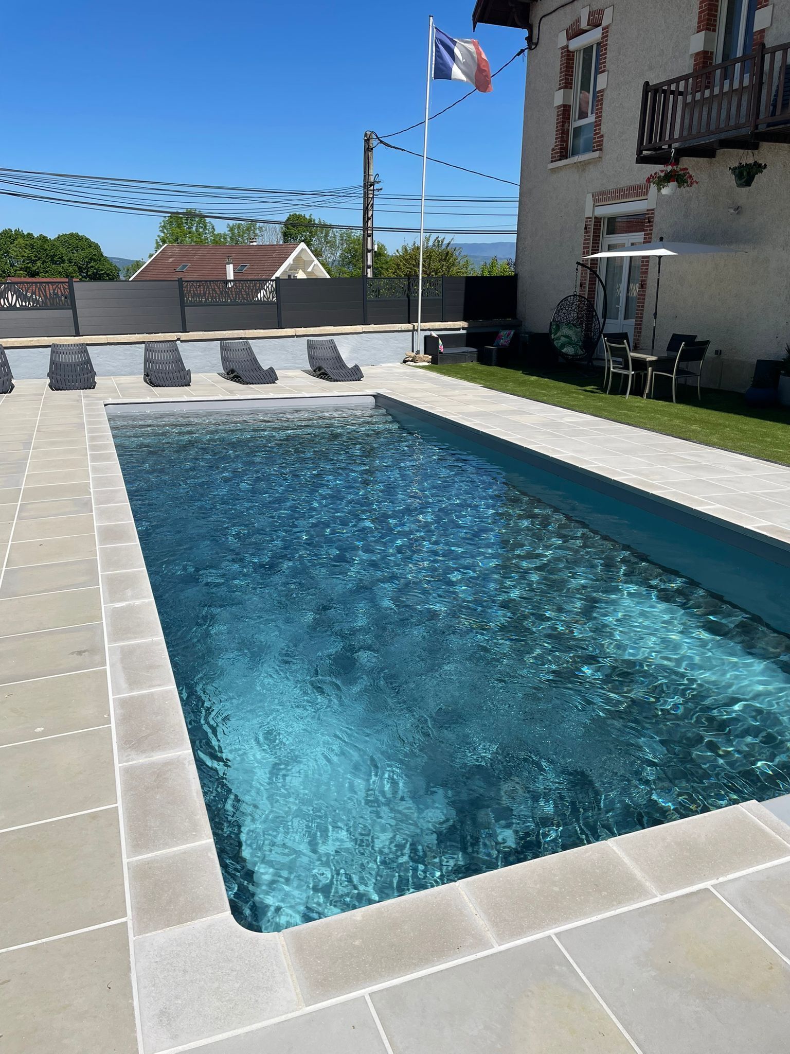A rectangular swimming pool with clear water, surrounded by a tiled deck.