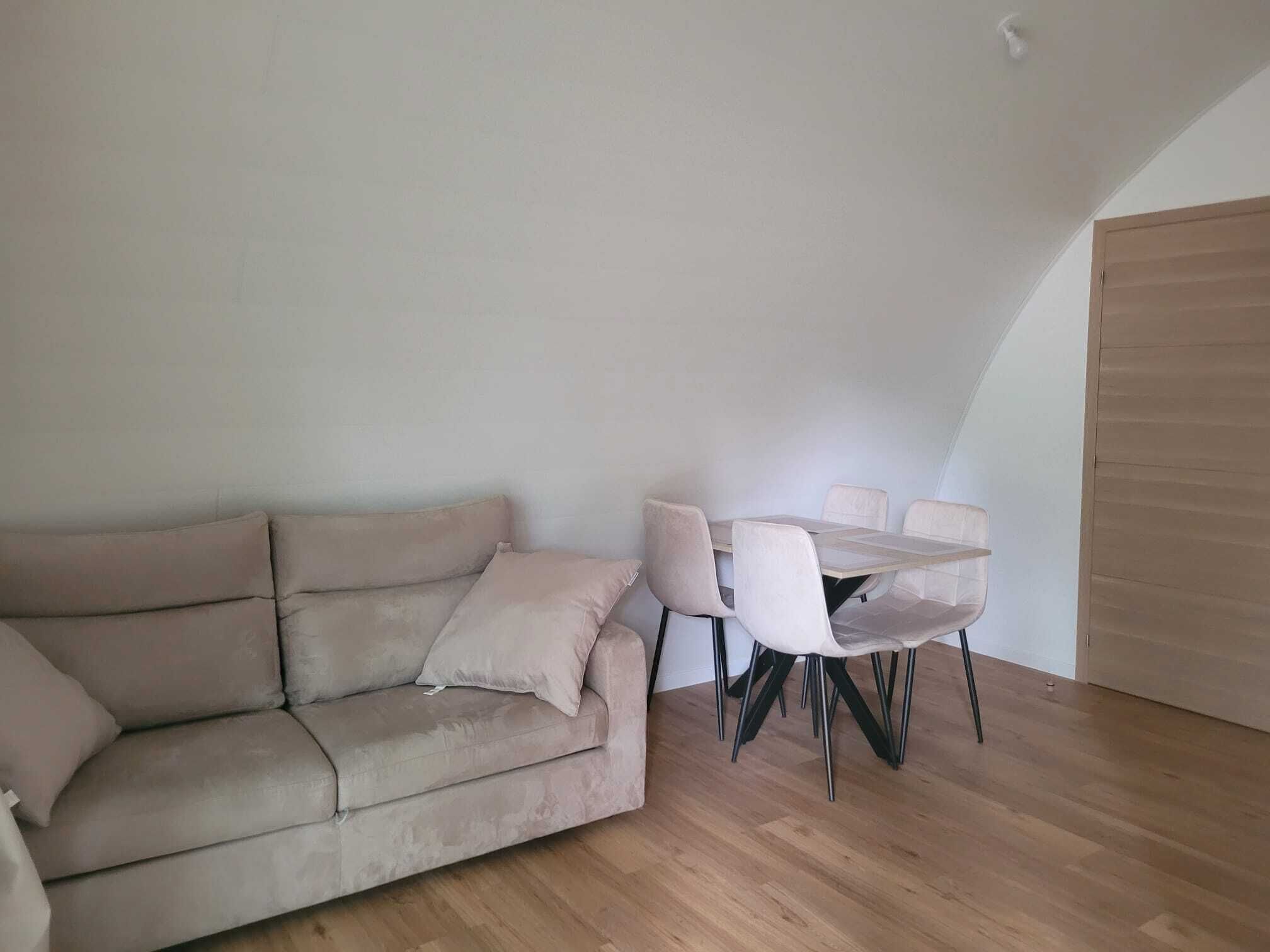 Una habitación con sofá, una mesa con sillas y una puerta de madera.