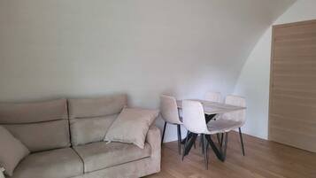 Una habitación con sofá, una mesa con sillas y una puerta de madera.