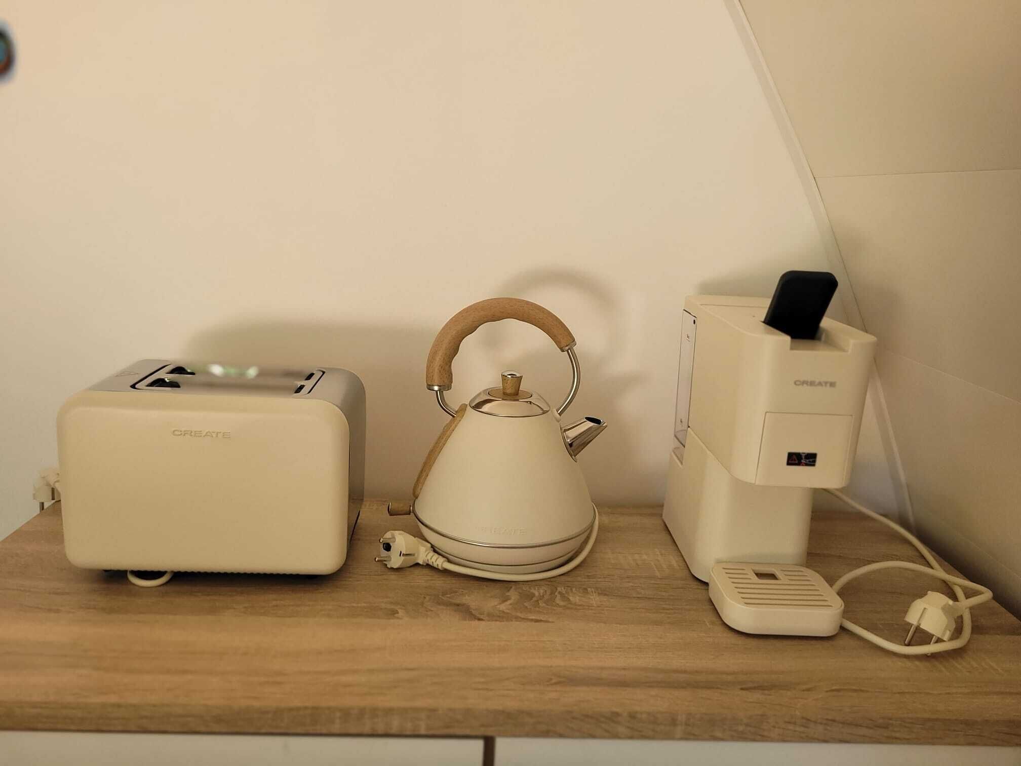 A kitchen with a toaster, kettle, and coffee maker on a wooden countertop.