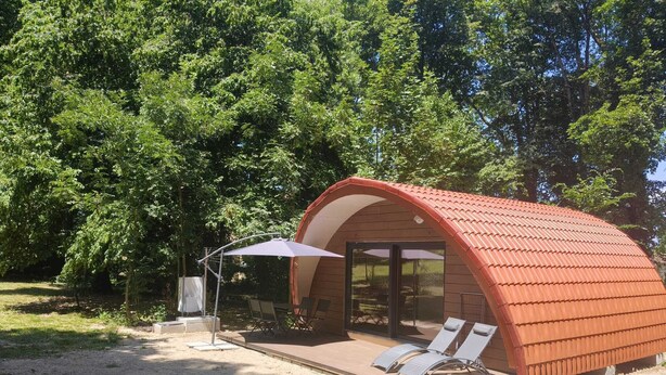 A small, curved-roofed structure with a patio area and lounge chairs.