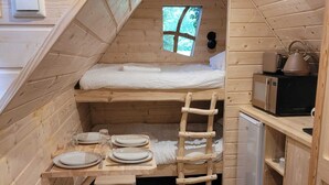A compact wooden cabin with a loft bed, a small kitchenette, and a dining area.