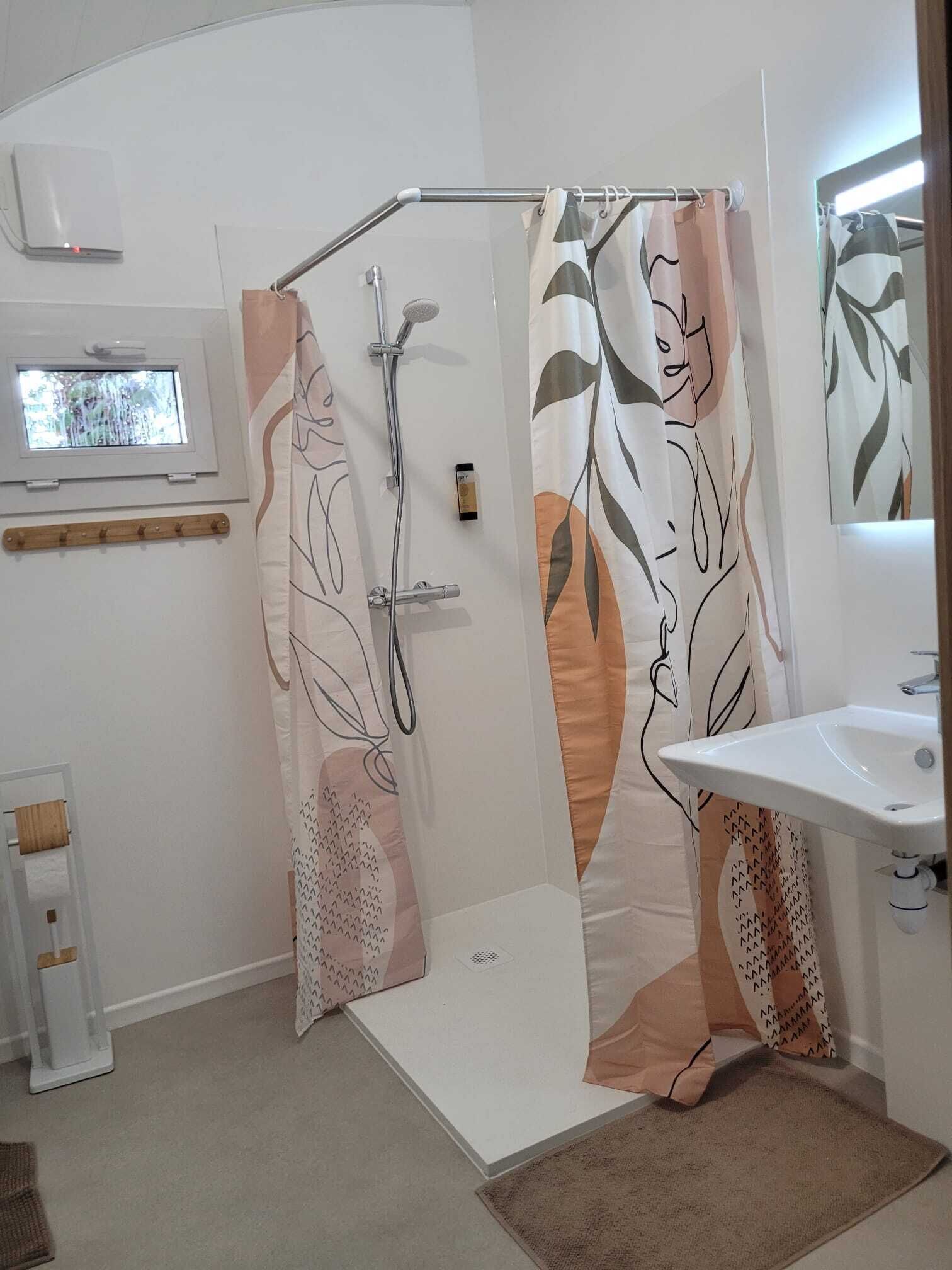 Un baño con ducha, lavamanos y ventana.
