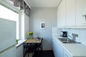 A compact kitchen with a wooden table, two chairs, a coffee maker, and a sink. - Stylish Studio Apt in Kemi (Kemi)