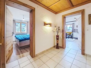 Ein Zimmer mit einem Bett, einer Vase mit Blumen und einem Essbereich im Hintergrund.