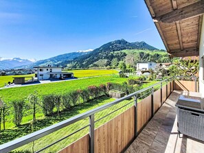 Ein Balkon mit Blick auf ein grünes Feld, einen Berg und ein weißes Gebäude.
