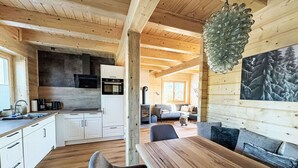 Ein modernes Interieur einer Blockhütte mit Küche, Essbereich und Wohnraum.