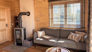 Ein gemütliches Blockhaus-Interieur mit einer Couch, einem Kamin und einem Fenster mit Jalousien.