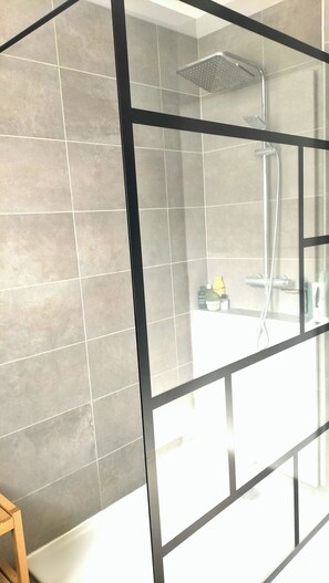 A bathroom with grey tiles, a shower, and a wooden stool. - At the foot of the hill, 2 min from the river (Sorgue), 5 min from Isle sur Sorgue! (Saumane-de-Vaucluse)