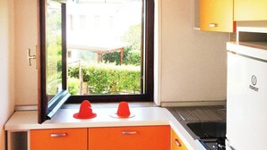 A kitchen with orange cabinets, a window, and a white refrigerator. - Residence La Giungla (Falerna)