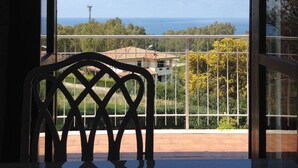 A room with a view of the sea, a balcony with a metal railing, and a chair in the foreground. - Residence La Giungla (Falerna)