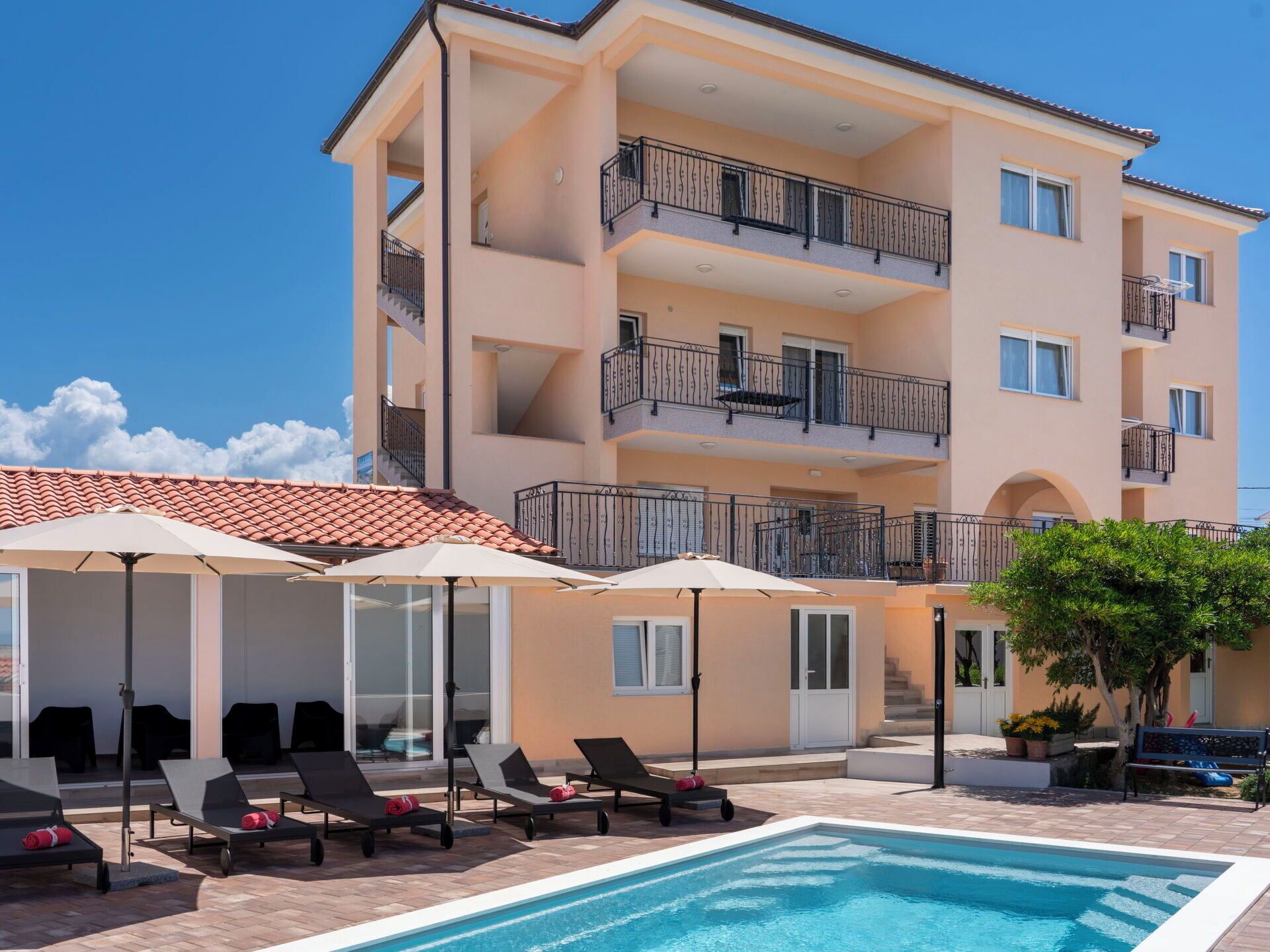 A multi-story hotel with a swimming pool, outdoor seating, and balconies.