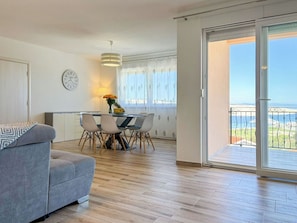 Eine moderne Wohnung mit Essbereich, einer Couch, einer Uhr und einem Balkon mit Blick.