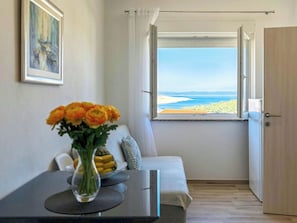 Ein Zimmer mit Meerblick, einer Couch, einem Tisch mit Blumenvase und einer Tür.