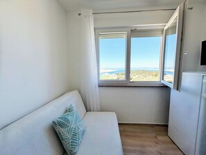 Ein kleiner Raum mit einem weißen Sofa, einem Fenster mit Blick auf eine Landschaft und einem weißen Gerät.