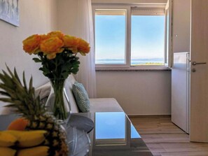 Ein Zimmer mit Tisch, einer Blumenvase, einem Fenster mit Aussicht und einer Tür.
