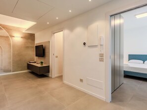 A modern hotel room with a flat-screen TV, a bedside telephone, and a bed with a blue headboard. - Nice apartment for 4 people with A/C and patio (Colico)