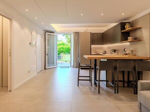 Een moderne keuken met een eethoek, een schuifpui naar een tuin en een flatscreen televisie aan de muur.