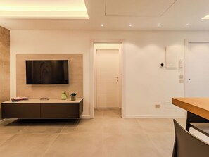 Ein modernes Wohnzimmer mit Flachbildfernseher an der Wand, einem Holzesstisch und einer eingebauten Unterhaltungsecke.