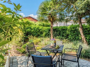 An outdoor patio with a table and chairs, surrounded by greenery and trees. - Nice apartment for 4 people with A/C and patio (Colico)
