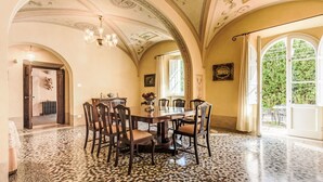 Ein Esszimmer mit Mosaikboden, einer Kristallleuchtre und Blick auf Grünflächen.